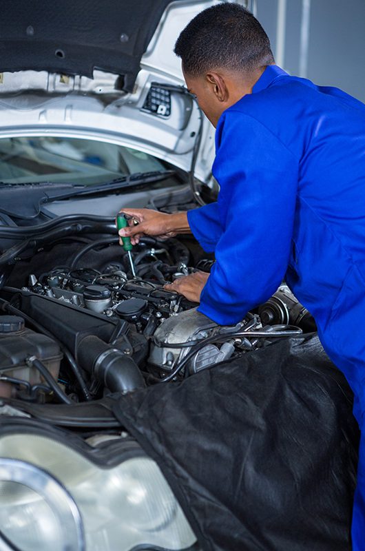 Mechanic servicing a car engine Attentive mechanic servicing automobile car engine in repair garage